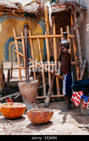 Meulage garçon mil en mode traditionnel, Djenné, Mali. Banque D'Images