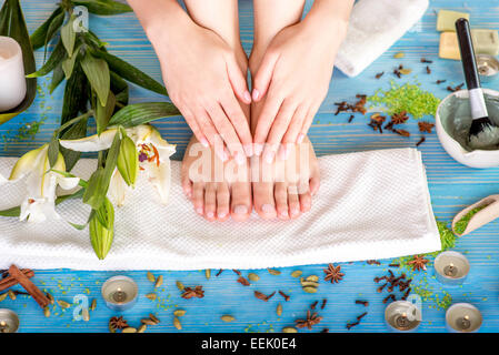 Femme prendre soin de ses jambes sur la serviette de bain avec des fleurs, des bougies et des herbes sur un bureau en bois bleu Banque D'Images