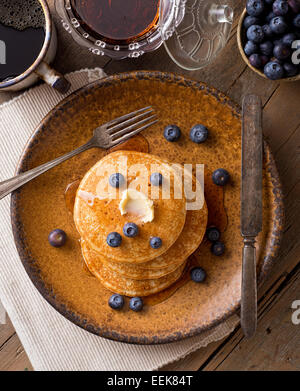 Pancakes aux myrtilles et sirop d'érable sur une table rustique. Banque D'Images