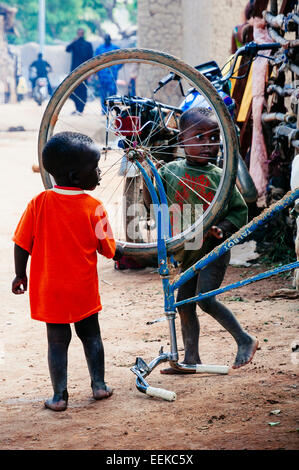 Enfants jouant avec une roue de vélo dans les rues de Djenné, Mali Banque D'Images