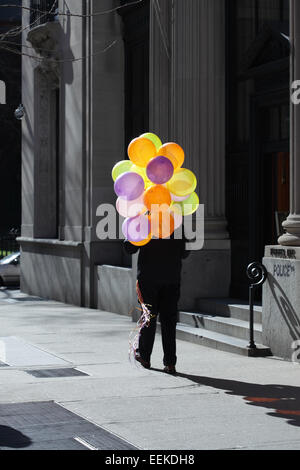 Man Walking down 5th Avenue New York street avec un grand groupe de ballons colorés Banque D'Images