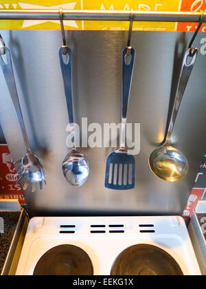 Des ustensiles de cuisine accroché sur rail sur cooker Banque D'Images