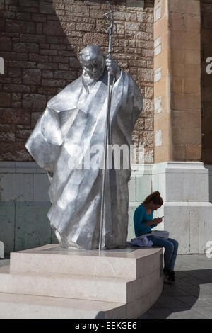 Une fille assise à la base de la statue créée par Karol Wojtyla né Sarajevo sculpteur Hrvoje Uremovic devant Jésus Sacre Banque D'Images