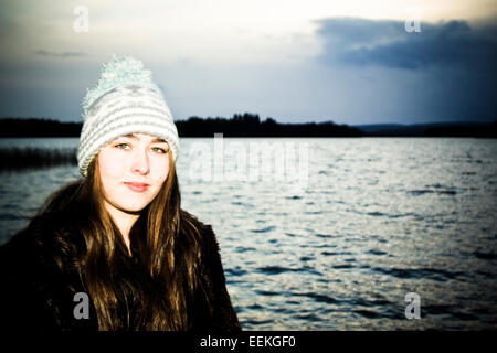 Traitées portrait of young woman standing by lake Banque D'Images