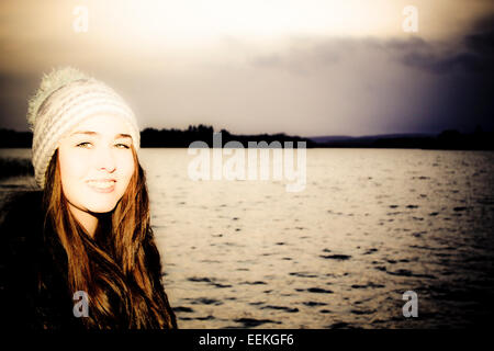 Traitées portrait of young woman standing by lake Banque D'Images