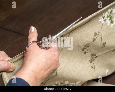 Gros plan du senior woman's hands cutting , dans la moitié à l'aide de ciseaux Banque D'Images