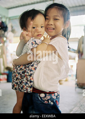 Vietnamese girl holding baby, faisant signe de la paix Banque D'Images