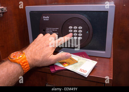 Personne de la saisie d'un axe dans un coffre fermé, carte de crédit, des passeports et l'argent se trouvant en face du coffre-fort, dans une chambre d'hôtel Banque D'Images