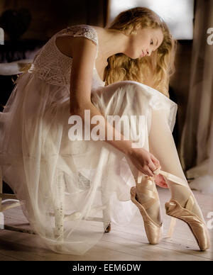 Jeune danseuse de ballet en robe blanche préparer des rubans chaussures de ballet Banque D'Images