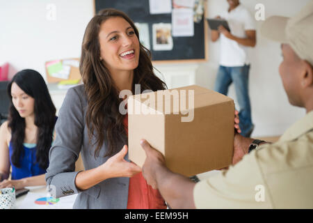 Delivery man handing boîte en carton de businesswoman in office Banque D'Images