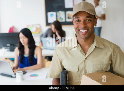 Delivery man smiling in office Banque D'Images