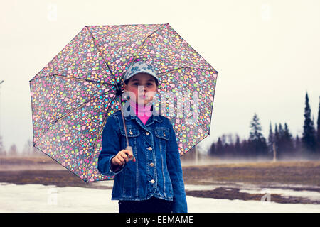 Caucasian girl walking under umbrella in snowy field Banque D'Images