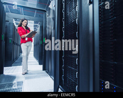 Caucasian businesswoman reading clipboard in server room Banque D'Images