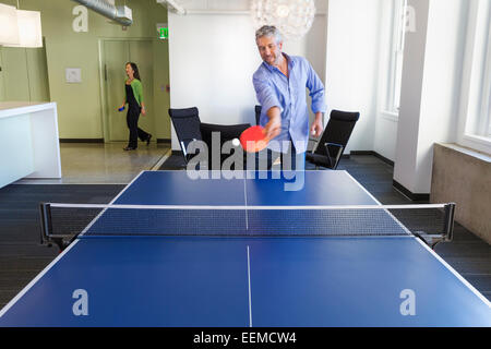 Businessman à jouer au tennis de table in office Banque D'Images