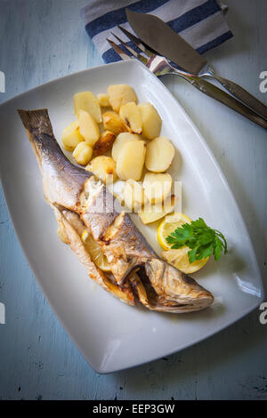 Le loup de mer frais cuit avec pommes de terre et citron Banque D'Images