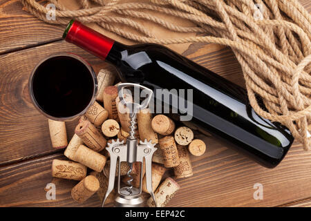 Bouteille de vin rouge, verre, bouchons et tire-bouchon. Vue de dessus sur fond de table en bois rustique Banque D'Images