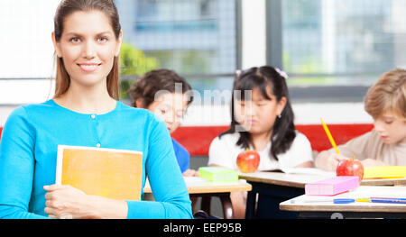 Heureux enseignante dans une classe élémentaire ethniques. Banque D'Images