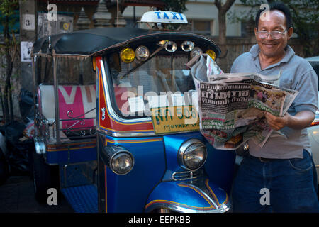 Tuk Tuk driver lire le journal. Tuk-tuks ou 'sam lor' (trois roues) utilisé pour être le favori de tous moyens de locomotion dans Banque D'Images