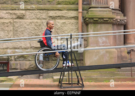 L'homme en fauteuil roulant avec la méningite à l'aide d'une rampe d'accès Banque D'Images