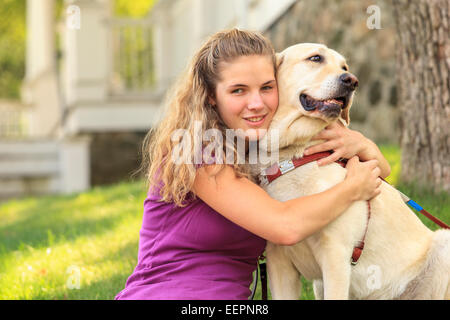 Femme avec déficience visuelle serrant son chien aidant Banque D'Images