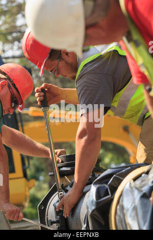 Les travailleurs de la construction à l'aide d'une clé dynamométrique pour la sécurité de l'eau section principale avec des boulons Banque D'Images