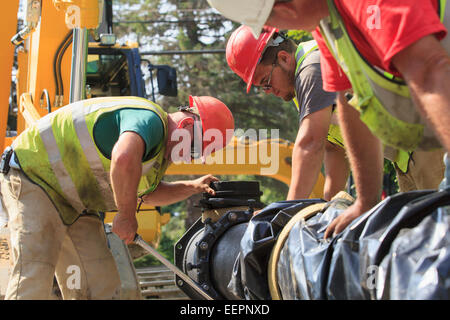 Les travailleurs de la construction à l'aide d'une clé dynamométrique pour la sécurité de l'eau section principale avec des boulons Banque D'Images