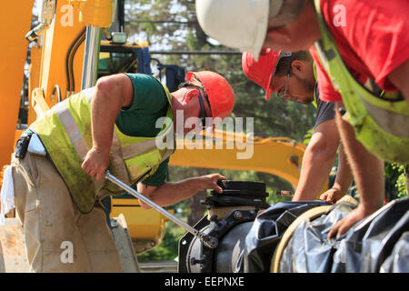 Les travailleurs de la construction à l'aide d'une clé dynamométrique pour la sécurité de l'eau section principale avec des boulons Banque D'Images