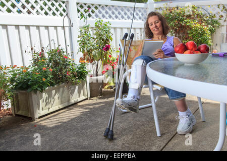 Femme avec le spina-bifida Rédaction de notes tout en vous reposant dans une attelle de jambe Banque D'Images