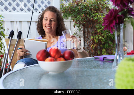 Femme avec le spina-bifida Rédaction de notes tout en vous relaxant sur patio Banque D'Images