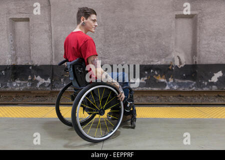 L'homme à la mode avec un fauteuil roulant dans la moelle épinière en attente d'une rame de métro Banque D'Images