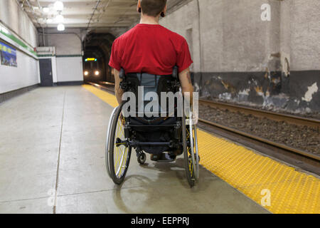 L'homme à la mode avec un fauteuil roulant dans la moelle épinière en attente d'une rame de métro Banque D'Images
