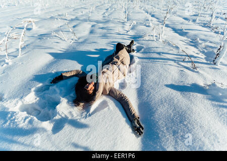 Belle brunette girl smiling et couché sur la neige Banque D'Images