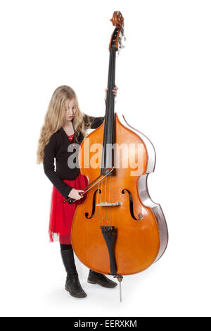 Jeune fille blonde en robe rouge joue la contrebasse dans studio against white background Banque D'Images