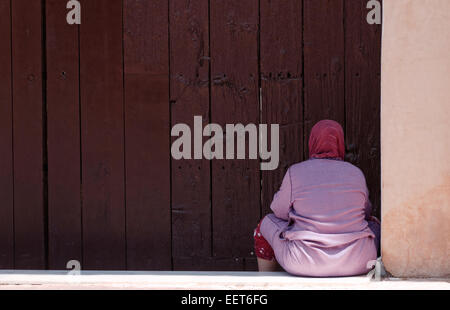 Femme assise à l'ombre d'une mosquée porte entrée porte, Marrakech, Maroc Banque D'Images