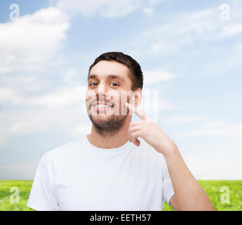 Smiling young man pointing to cheek Banque D'Images