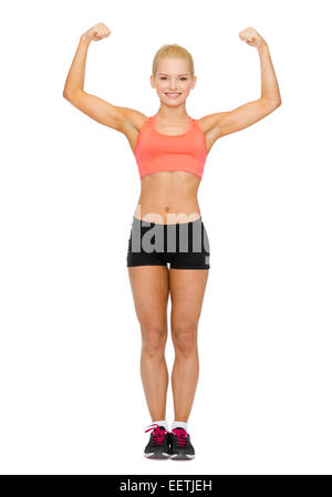 Smiling sporty woman flexing biceps sa Banque D'Images