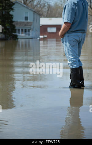 Homme debout avec les mains dans les poches à la rue inondée à Banque D'Images