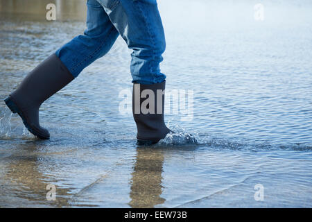 Man wading in rue inondée Banque D'Images