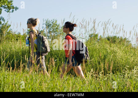 Deux amies de la randonnée à travers la tenue d'herbe de l'eau en bouteille Banque D'Images