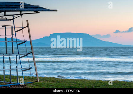 Lac Balaton glacées en hiver par le lever du soleil, la Hongrie. L'Hotel Mountain en arrière-plan. Banque D'Images