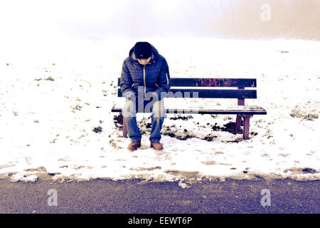 Homme assis sur un banc en hiver Banque D'Images