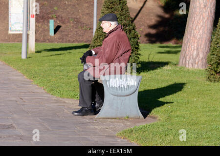 Homme assis sur un banc de parc sur froide journée d'hiver au château de Bedford, Bedford, Bedfordshire, Angleterre Banque D'Images