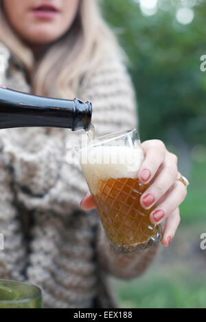 Apple orchard. Woman pouring un verre de cidre. Banque D'Images