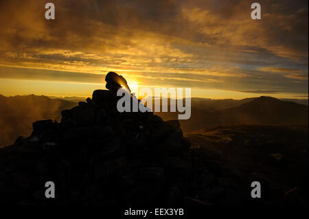 Une vue d'une silhouette du cairn au sommet de la montagne Suilven au lever du soleil, Ecosse, Royaume-Uni. Banque D'Images