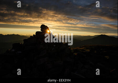 Une vue d'une silhouette du cairn au sommet de la montagne Suilven au lever du soleil, Ecosse, Royaume-Uni. Banque D'Images