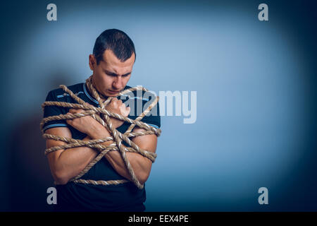 L'homme d'apparence brunet attachés avec une corde accroché sa Banque D'Images