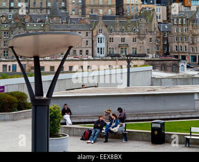 Des gens assis sur des bancs dans le centre-ville près de Princes Street Edinburgh Scotland UK avec la vieille ville à l'arrière-plan Banque D'Images