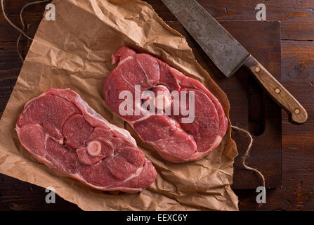 Tranches de gigot d'agneau sur papier boucher avec le couteau et le. Banque D'Images