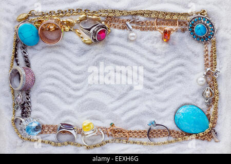 Des chaînes en or et des bijoux magnifiques sur mer sable blanc résumé cadre. Banque D'Images