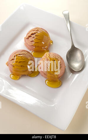 La crème glacée à la fraise et d'abricot au miel d'acacia sur une plaque blanche Banque D'Images